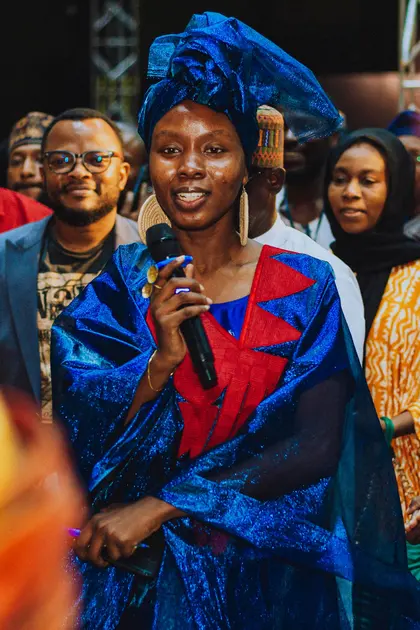 A speaker in a blue headwrap addressing visitors at KAFART 2023.