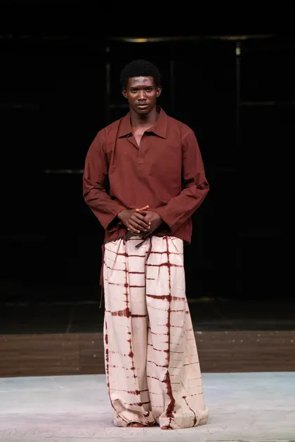 A model in a rust-coloured shirt and patterned trousers on the KAFART runway in 2024.