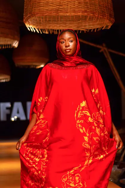 A model wearing a red design on the KAFART runway in 2022.